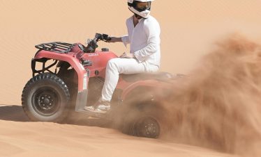 Person riding an ATV through sandy dunes in Merzouga, Morocco.