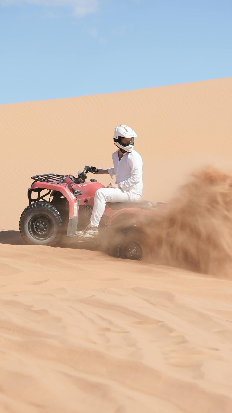 Person riding an ATV through sandy dunes in Merzouga, Morocco.