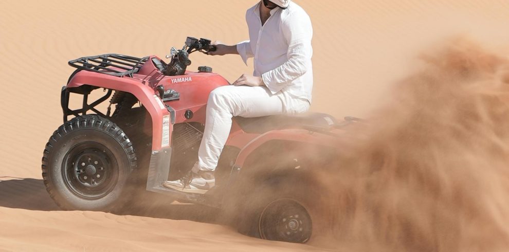 Person riding an ATV through sandy dunes in Merzouga, Morocco.